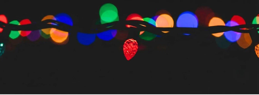 A glowing red C9 LED bulb vividly contrasted against darkness, with bokeh-blurred lights of various colors behind it.