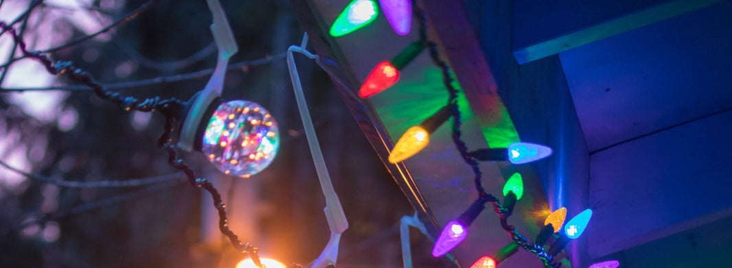 A closeup of the underside of a roof edge, where various Christmas lights and sparkly bulb lights hang together.