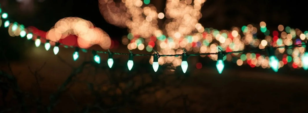 Close-up of a hanging line of lit-up green Christmas lights on a wire.